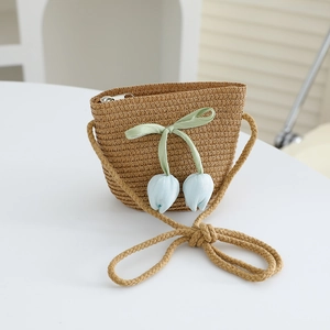 Detail view of woven straw crossbody bag with tulip floral charms and zip closure