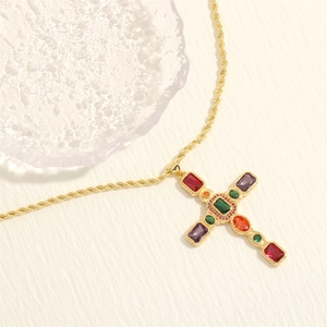 Dettaglio della collana a croce dorata con zirconi multicolori e catena a corda