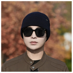 Close-up of navy blue winter knit beanie with fine texture and metal side label detail