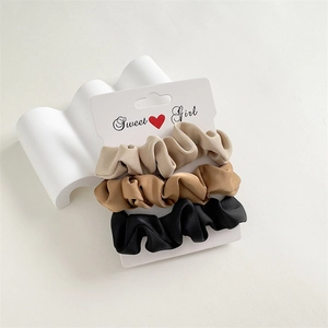 Lot de 3 chouchous en satin beige, marron et noir présentés sur une carte blanche