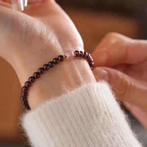 Detailed macro view of garnet and red agate beaded bracelet on a woman's wrist