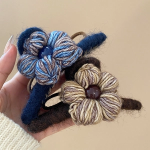 Gros plan d'une pince à cheveux fleur en maille avec texture de laine et centre en perle