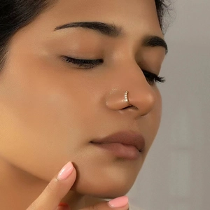 Detail of a minimalist gold star nose ring with sparkling crystals on a model side profile
