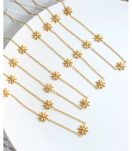 Macro view of several golden daisy charm necklaces on a white ceramic plate