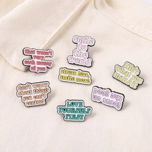 Close-up of seven colorful enamel pins with English quotes on corduroy fabric jacket
