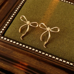 Détail de boucles d'oreilles nœud doré élégantes sur une texture en velours vert foncé