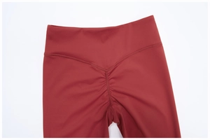 Détail du legging de yoga bordeaux à taille haute avec couture en V et effet froncé