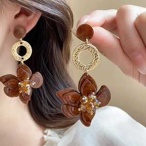 Brown flower earrings with golden rings on female model for a chic aesthetic look