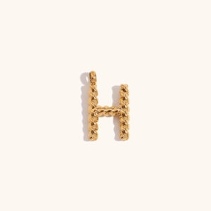 Macro detail of 18K gold plated letter H pendant with braided rope texture design