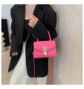 Detail of pink croc-effect mini bag with gold bar metal clasps on a stylish model outfit