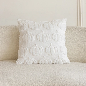 Detail of white plush pillow cover with 3D pumpkin embroidery on a beige sofa