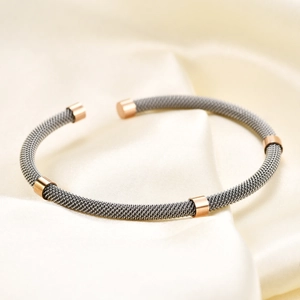 Detail view of woven stainless steel cable bracelet in charcoal grey and rose gold finish