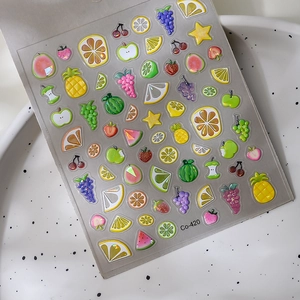 3D fruit nail art stickers with pineapple and strawberry designs on a ceramic plate