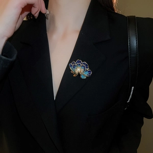 Macro detail of blue enamel flower brooch with large pearl on a black blazer jacket