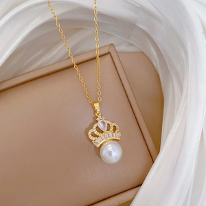 Macro detail of crown-shaped pendant with white pearl and diamonds on a gold chain