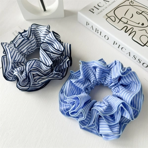 Schicke blau-weiß gestreifte Stoff-Scrunchies Set auf minimalistischem Hintergrund