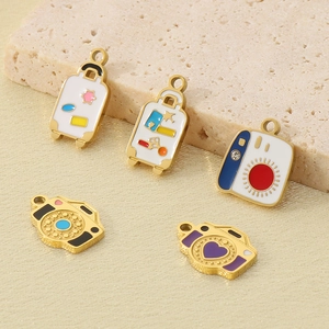 Macro shot of colorful enamel suitcase and camera pendants in gold-plated stainless steel