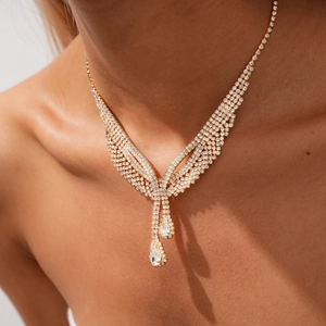 Close-up of luxury gold teardrop pendant necklace with sparkling rhinestone tassels on model