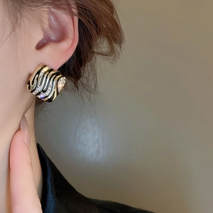 Close-up of vintage gold and black geometric earring worn by a model in soft lighting