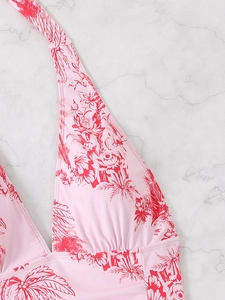 Close-up of pink halter swimsuit with tropical red floral print and v-neck detail