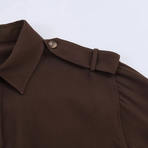 Détail de l'épaulette de chemise marron avec bouton et texture de tissu tissé