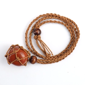 Detail of red raw crystal stone in a brown handcrafted woven net pendant necklace