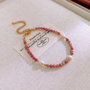 Detailed shot of pink stone and pearl beaded bracelet with gold lobster clasp
