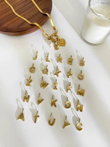 Artistic layout of golden letter charms and heart pearl pendants on flat snake chains