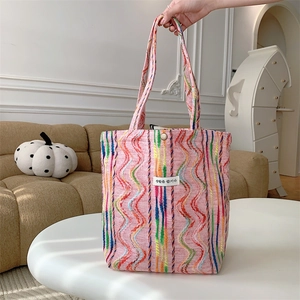 Détail du sac cabas à motifs vagues arc-en-ciel avec écusson coréen sur table blanche