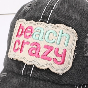 Close-up of beach crazy embroidery and distressed washed grey fabric on baseball cap