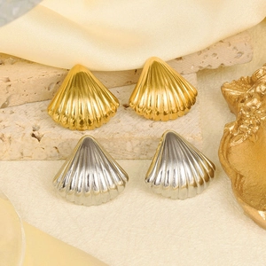 Macro detail of 18k gold and silver shell earrings on a neutral stone display tray
