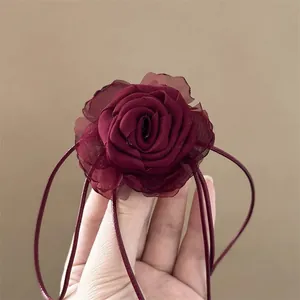 Detailed close-up of a burgundy lace rose hair tie and choker with adjustable ribbons