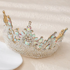 Golden Baroque bridal crown with iridescent pink crystals and beads on a beige texture