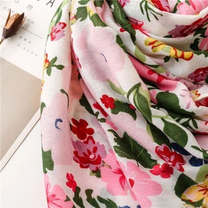 Detailed close-up showing vibrant floral prints and textured linen fabric of the scarf