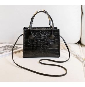 Détail du sac à main noir motif crocodile avec foulard en soie enroulé sur l'anse