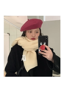 Detail of off-white ribbed knit scarf texture with woven label and pink beret