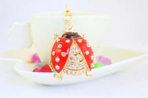 Close-up of a crystal rhinestone ladybug keychain with red enamel wings and gold chain