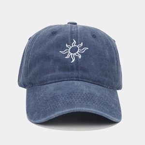 Close-up of white sun embroidery on washed vintage dark blue denim baseball cap