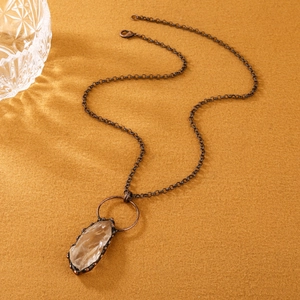 Dettaglio del pendente in cristallo grezzo su catena in bronzo antico con riflessi