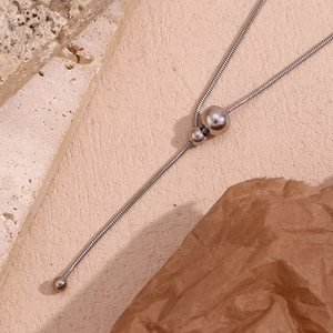 Macro shot of silver snake chain with polished metal beads on minimalist Y necklace