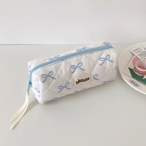 Detail of quilted white pencil case with blue bow patterns and light blue zipper closure