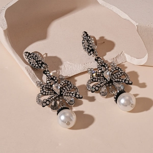 Detail view of vintage bow earrings with black metal, crystals and drop faux pearls