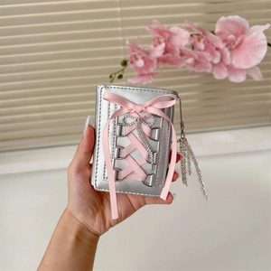 Detail of silver balletcore wallet with pink ribbons and a sparkly bow decoration