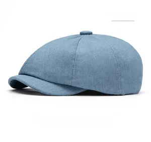 Close-up of light blue denim newsboy cap showing six-panel stitching and top button detail
