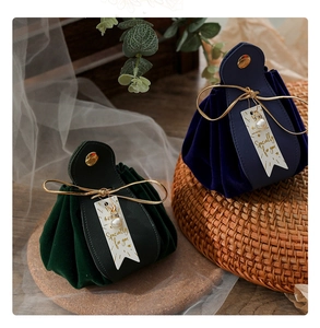 Detail of velvet wedding favor bags in navy and dark green with pearls and ribbons