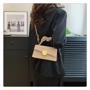 Gros plan du sac à bandoulière plissé beige avec fermoir métallique doré rond