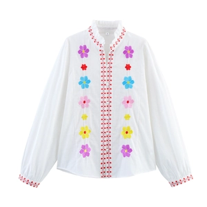 White long-sleeve embroidered blouse with colorful floral patterns and red wave trim