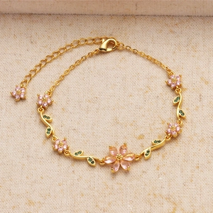 Macro shot of gold cherry blossom bracelet with pink zircon petals on beige linen