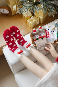 Close-up of fluffy coral fleece Christmas socks with festive cartoon designs in gift box