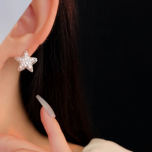 Macro detail of silver star earring with pavé zircon crystals on a model's ear